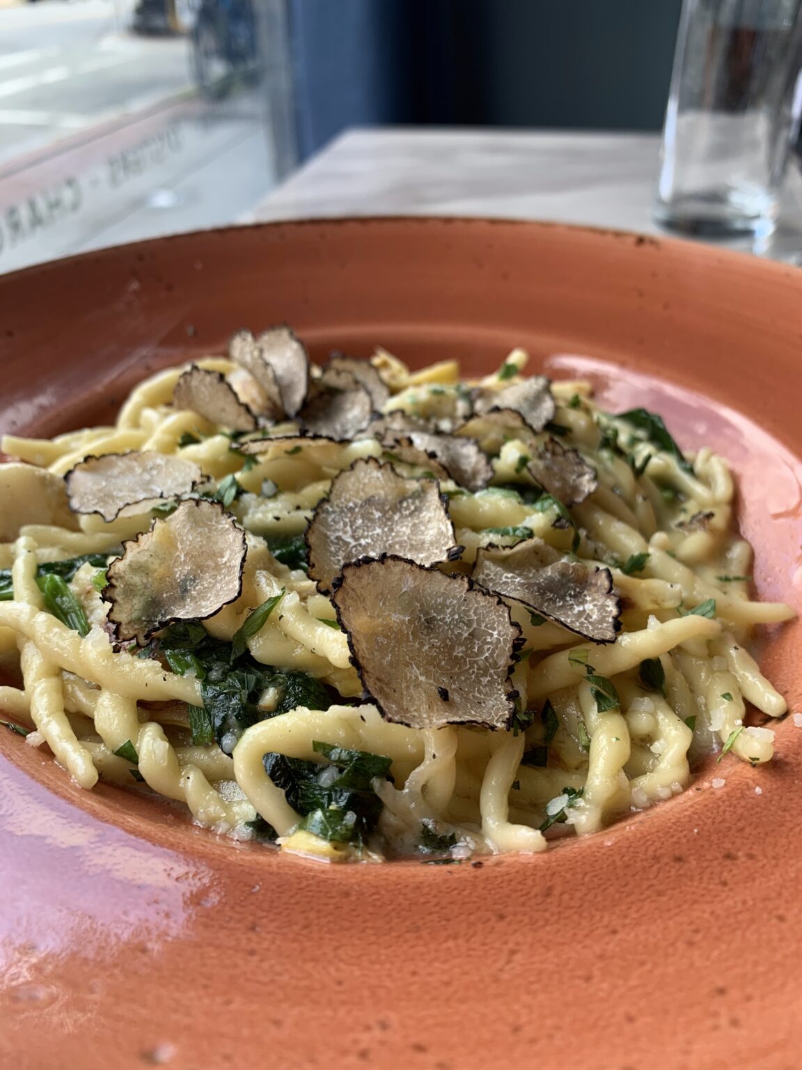 Pasta and truffles on an orange bowl.