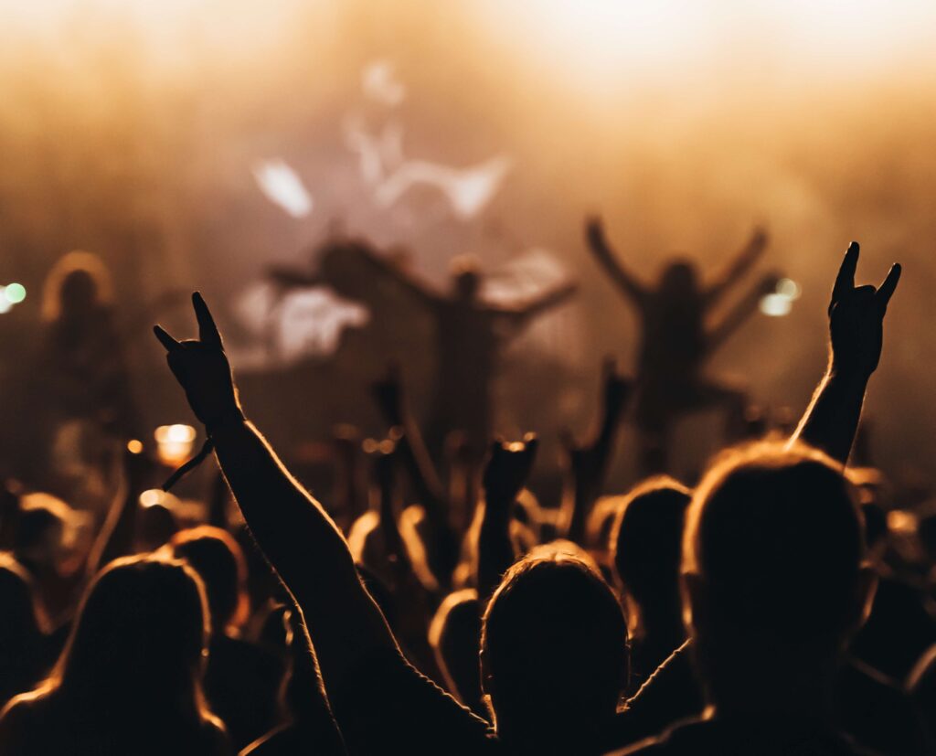 Cityscape of Cambridge, Massachusetts at dusk, with illuminated office buildings and high-rises reflecting on the calm waters of the Charles River under a pastel pink and blue sky.