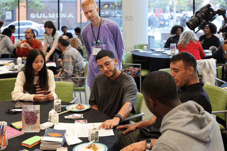 People gathered around paper, talking and working