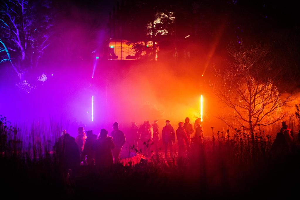 People walking through a purple and orange light show