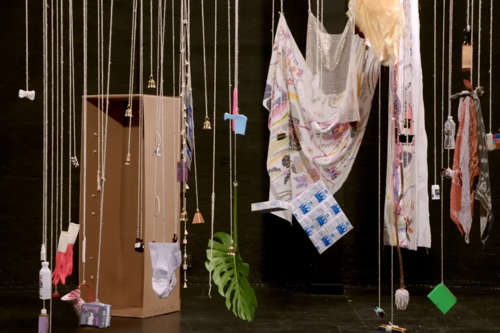 Different kinds of objects, such as Advil, a water bottle and more hanging from strings as an art exhibit.